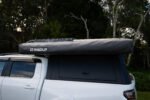 Side profile of the Rigdup 270 degree awning mounted and packed on a white ute canopy with roof rack